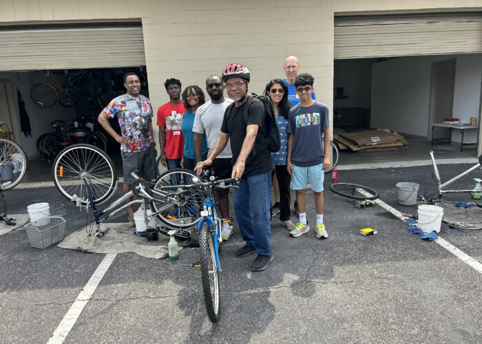 A group of people standing around a bike.